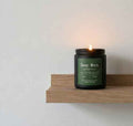Black aromatherapy candle labeled Deep Work with eucalyptus mint scent, soy wax, on a wooden shelf, lit for focus and clarity